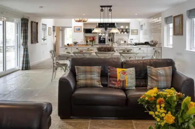 a living room with a brown couch and a kitchen at Laverockbank Farmhouse in Perth