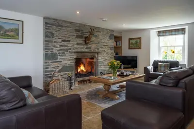a living room with couches and a stone fireplace at Laverockbank Farmhouse in Perth