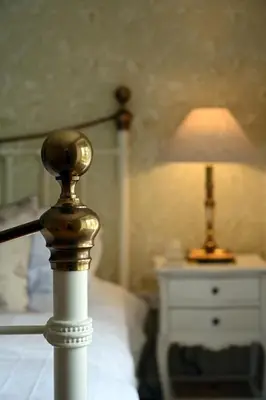 a lamp on a bed next to a white night stand at Laverockbank Farmhouse in Perth