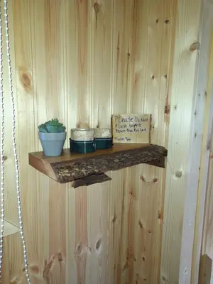 a shelf on a wooden wall with pots and a sign at Sunset View Shepherds Hut in Dalmally