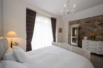 a bedroom with a white bed and a stone wall at Coach House in Perth