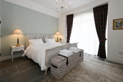a bedroom with a large bed and a chandelier at Coach House in Perth