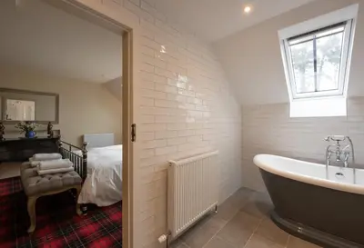 a bathroom with a bath tub and a bed at Coach House in Perth