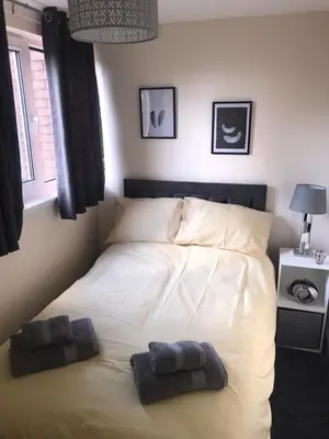 a bed in a bedroom with two towels on it at Vogue Apartments in Glasgow