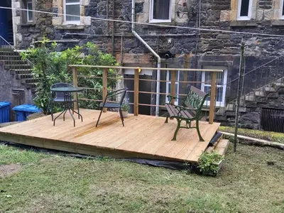 two chairs and a table on a wooden deck at One bedroom flat, very close to Town center. in Oban