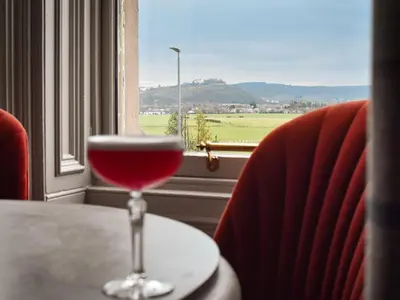 a glass of wine sitting on a table in front of a window at The Meadowpark Bar, Kitchen & Rooms in Stirling