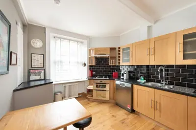 a kitchen with wooden cabinets and a wooden table at Charming Grassmarket 1 Bed Castle pad in Edinburgh