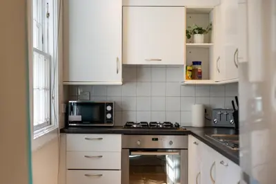 a kitchen with white cabinets and a microwave at Lovely 3 bed apartment in central Edinburgh in Edinburgh