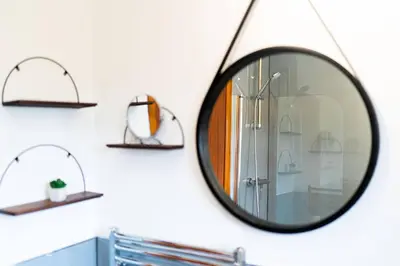 a mirror hanging on a bathroom wall with shelves at The Tollbooth in Clackmannan