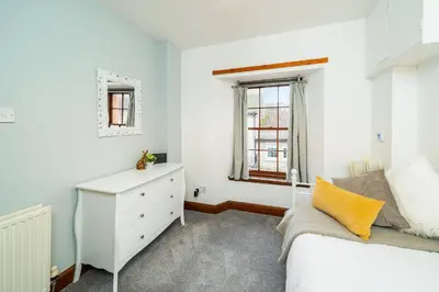 a bedroom with a bed and a dresser and a window at The Tollbooth in Clackmannan