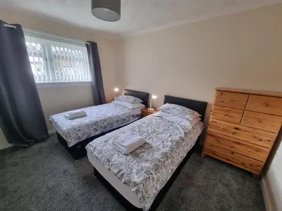 a bedroom with two beds and a dresser and a window at Hamilton Home From Home in Hamilton
