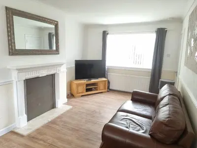 a living room with a leather couch and a television at Hamilton Home From Home in Hamilton