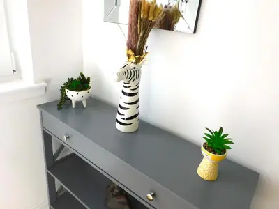 a gray console table with two vases and plants on it at Newly refurbished 2 bedroom apartment close to station and local amenities in Hamilton