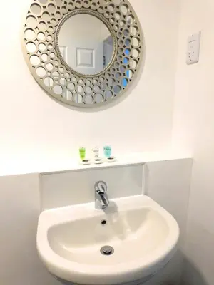 a bathroom with a white sink and a mirror at Newly refurbished 2 bedroom apartment close to station and local amenities in Hamilton
