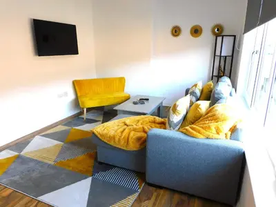 a living room with a couch and a chair at Newly refurbished 2 bedroom apartment close to station and local amenities in Hamilton