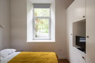 a bedroom with a yellow bed and a window at Artist's Studio in Stockbridge in Edinburgh