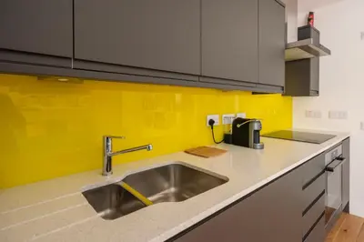 a kitchen with a sink and a yellow wall at Artist's Studio in Stockbridge in Edinburgh
