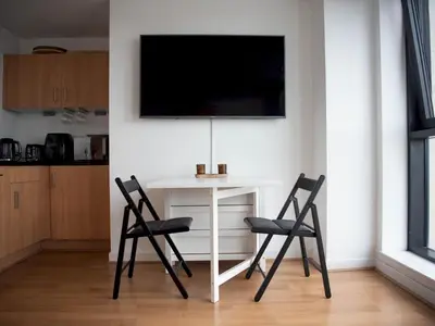a white table with two chairs and a tv on a wall at Cosy 1 bed next to SEC, OVO Hydro, Finnieston - Pass the Keys in Glasgow