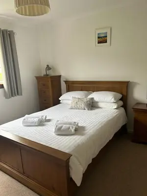 a bedroom with a large bed with two towels on it at Lyn leven cottages in Ballachulish