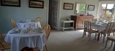 a dining room with tables and chairs with white tablecloths at CORSBIE VILLA GUEST HOUSE in Newton Stewart