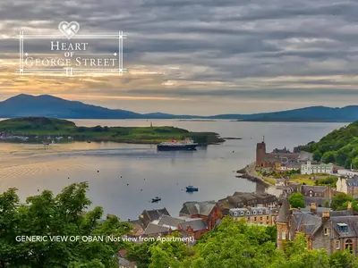 a view of a river with a town and a boat at Heart of George Street 2 in Oban