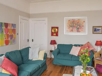 a living room with two blue couches and a table at The Seaside Suite in Helensburgh