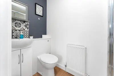 a white bathroom with a toilet and a sink at Cheerful Stays - Livingston - 4 Bedroom 3 Bath home in Livingston