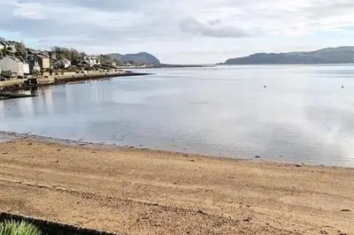 a beach with a body of water with houses at Loch Views Apartment Sleeps 2-Pets Ok-Free Parking in Campbeltown