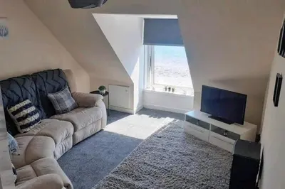 a living room with a couch and a flat screen tv at Loch Views Apartment Sleeps 2-Pets Ok-Free Parking in Campbeltown