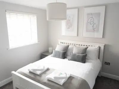 a bedroom with a white bed with two towels on it at Lovely, comfortable 2-bed Braehead - free parking - Pass the Keys in Renfrew
