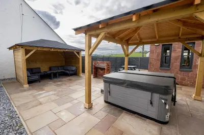 a patio with a barbecue grill and a pavilion at Westertonhill Holiday Lodges - Private Hot Tub Hire Available in Balloch