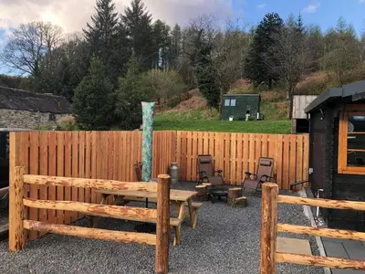 a wooden fence with a wooden table and chairs at 1 Bed Cabin in the Magical Galloway Forest Park in Newton Stewart