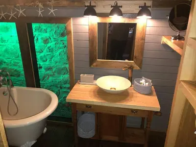 a bathroom with a tub and a sink and a mirror at 1 Bed Cabin in the Magical Galloway Forest Park in Newton Stewart