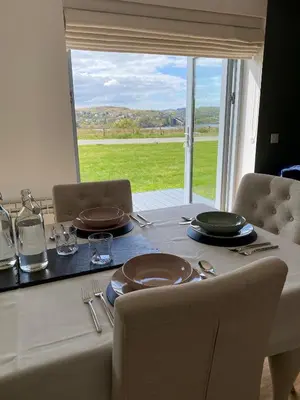 a table with plates and glasses on it with a window at No 2 The Cairns, Unwind in Style in Oban