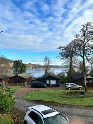 a car parked in front of a house with a lake at Cherry tree Lodge in Dunoon