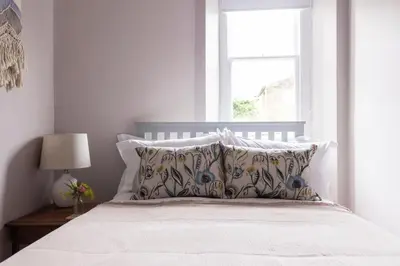 a bedroom with a bed with pillows and a window at The Wee Shop, Stylish Two Bed Flat in Inverkip Village in Inverkip