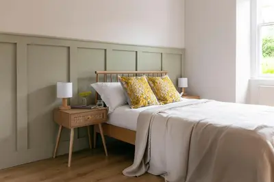 a bedroom with a bed with yellow pillows on it at The Wee Shop, Stylish Two Bed Flat in Inverkip Village in Inverkip