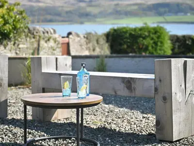 a bottle on a table with a glass on it at Taigh An Uillt in Tighnabruaich