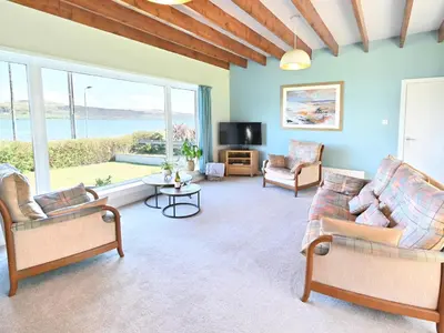 a living room with furniture and a large window at Taigh An Uillt in Tighnabruaich