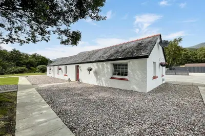 a white house with a gravel driveway at Unique restored Old Post Office in Kinlochleven