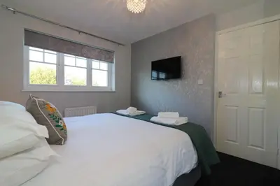 a bedroom with a large white bed and a window at Signature - Chapelhall House in Chapelhall
