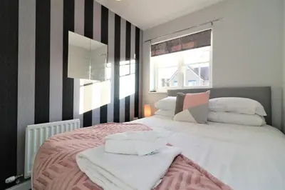 a bedroom with a large white bed with black and white stripes at Signature - Chapelhall House in Chapelhall