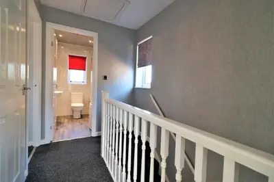 a hallway with a bathroom with a toilet and a sink at Signature - Chapelhall House in Chapelhall