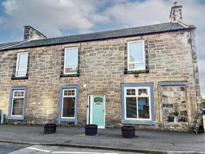 an old brick building with a green door and windows at 40 Main Street in Burntisland