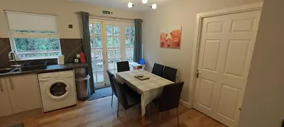 a kitchen and dining room with a table and a washing machine at Ben Reoch Cottage - Loch Lomond and Arrochar Alps in Tarbet