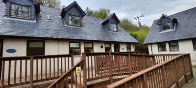 a home with a wooden deck and a house at Ben Reoch Cottage - Loch Lomond and Arrochar Alps in Tarbet