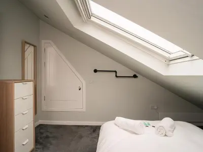 a bedroom with a bed with white sheets and a skylight at 2BD Loft Style Apt - Edinburgh - Free Parking - Pass the Keys in Edinburgh