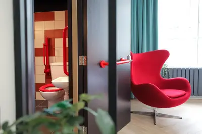 a red chair in a bathroom with a toilet at Revolver Glasgow in Glasgow