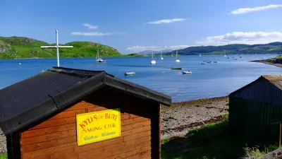 a dog house with a yellow sign on it next to a lake at Tighnabruaich Duplex Apartment - Sea Views in Tighnabruaich