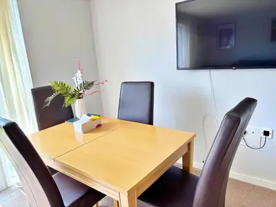 a wooden dining room table with chairs and a tv at Newbuild - 3 bedrooms, 2 baths,5 mins from airport in Edinburgh